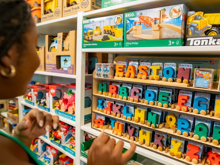 Eine Kundin sucht im Spielwarenregal zwischen Holzbuchstaben und Lernspielzeug